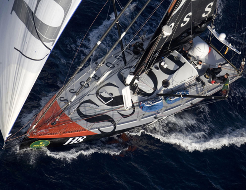 Alex Thomson's UK entry Hugo Boss powering downwind at sunrise on day 2 of the Rolex Sydney Hobart