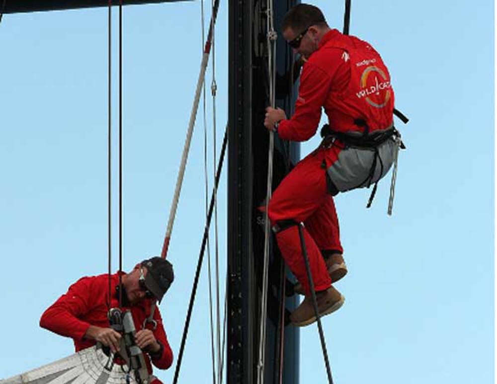 Wild Oats XI crew members Tim Wiseman and Sven Runow up the mast trying to bring down the square top main