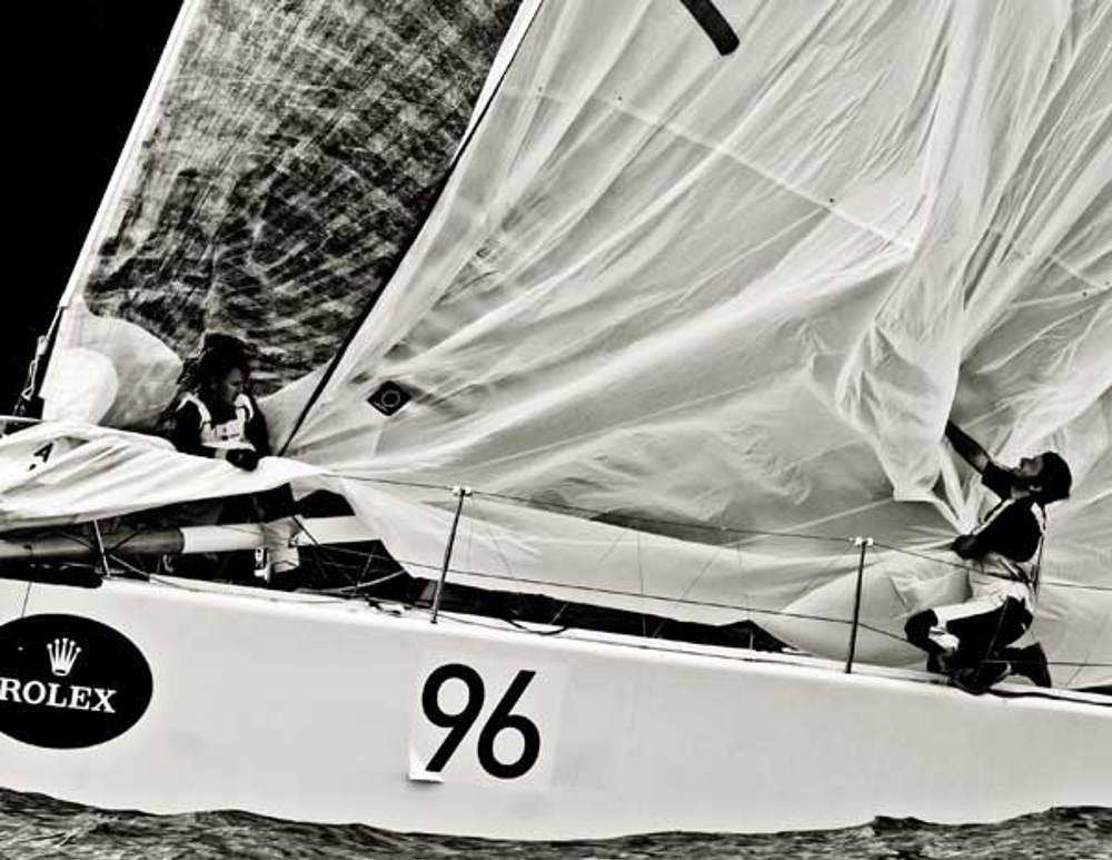Crew members onboard Vamp take down the spinnaker near the Organ Pipes