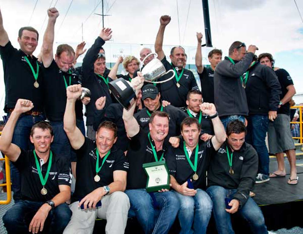 The crew of Investec Loyal celebrate after receiving the line honours trophy and Rolex timepiece