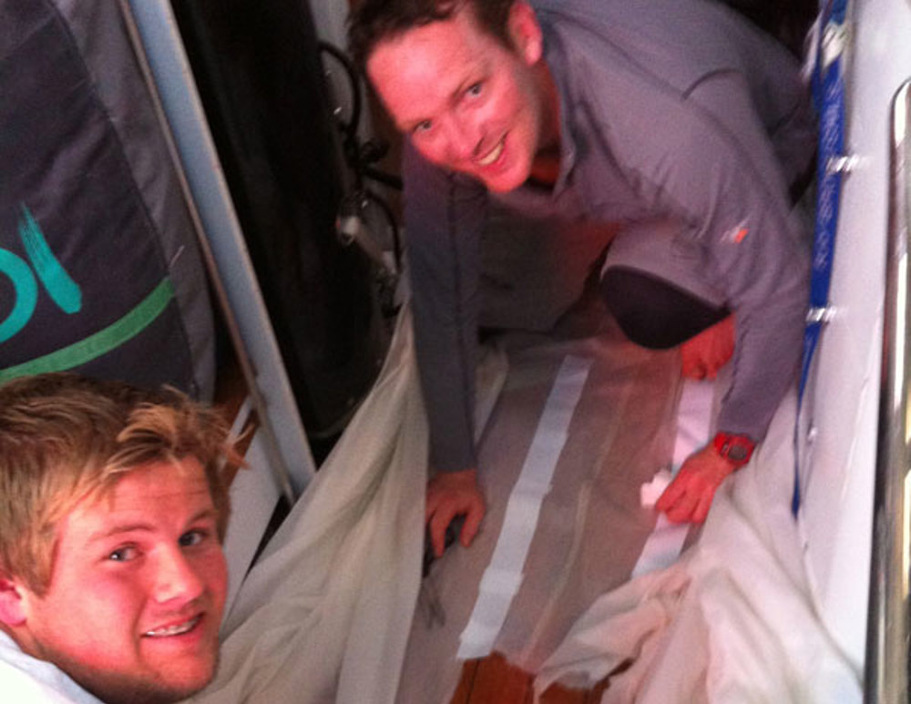 Ben and James in the Galley Mending Exile's Sails. Ben smelt dinner cooking, opened the oven door and the lasagne promptly flew out of the oven and onto the sail!