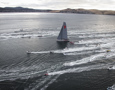 Wild Oats XI heads for the finish line surrounded by spectator craft