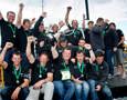 The crew of Investec Loyal celebrate after receiving the line honours trophy and Rolex timepiece