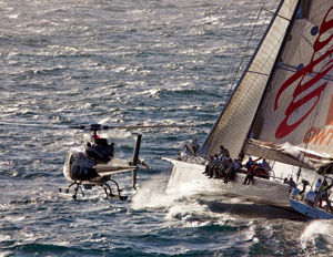 Neville Crichton's Alfa Romeo keeping close company with a helicopoter as it rounds Tasman Island